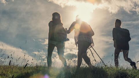 Drei Menschen wandern vor einem Sonnenuntergang, um ihre geistige Gesundheit zu stärken