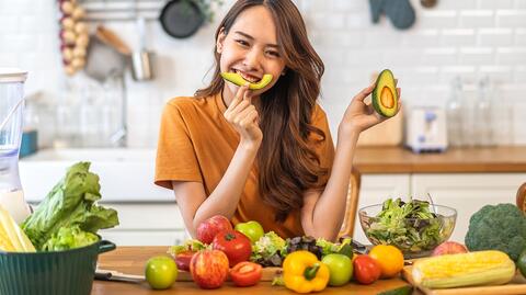 Eine Frau isst eine Avocado, ein perfektes Nahrungsmittel gegen Akne.