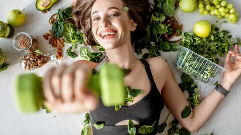 Frau auf dem Rücken liegend, eine Hantel hebend