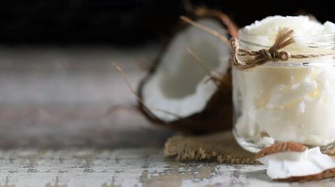 Eine halbe Kokosnuss und ihr Öl in einem Glas, oft zum Ölziehen verwendet