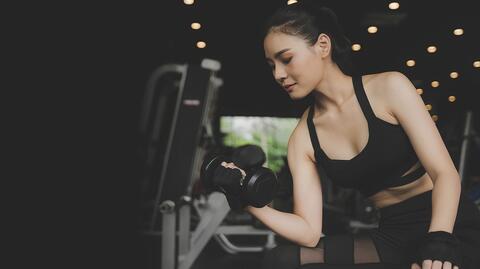 Frau trainiert Arme mit Gewichten
