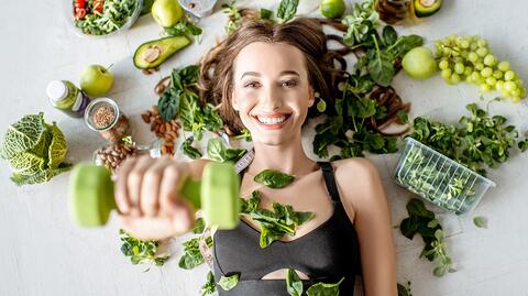 Eine Frau liegt im gesunden Grün und hält eine Hantel, um die Grundlagen der Leistung zu symbolisieren